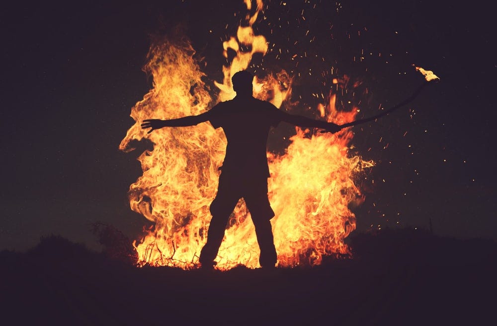 person standing in front of fire during night time person standing in front of fire during night time