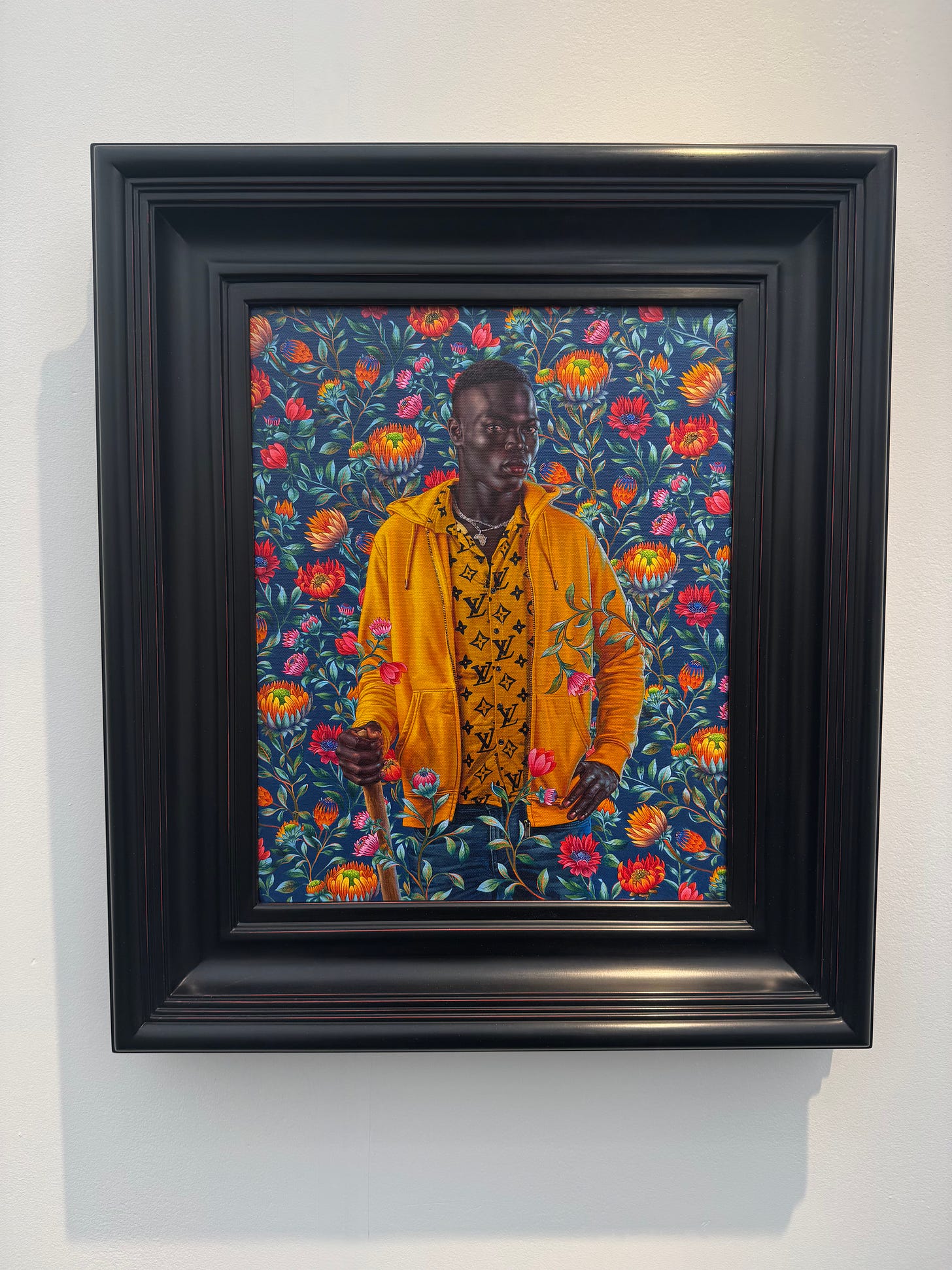 Framed portrait of Mamadou Gueye by Kehinde Wiley, with the subject in a patterned jacket against a floral backdrop.