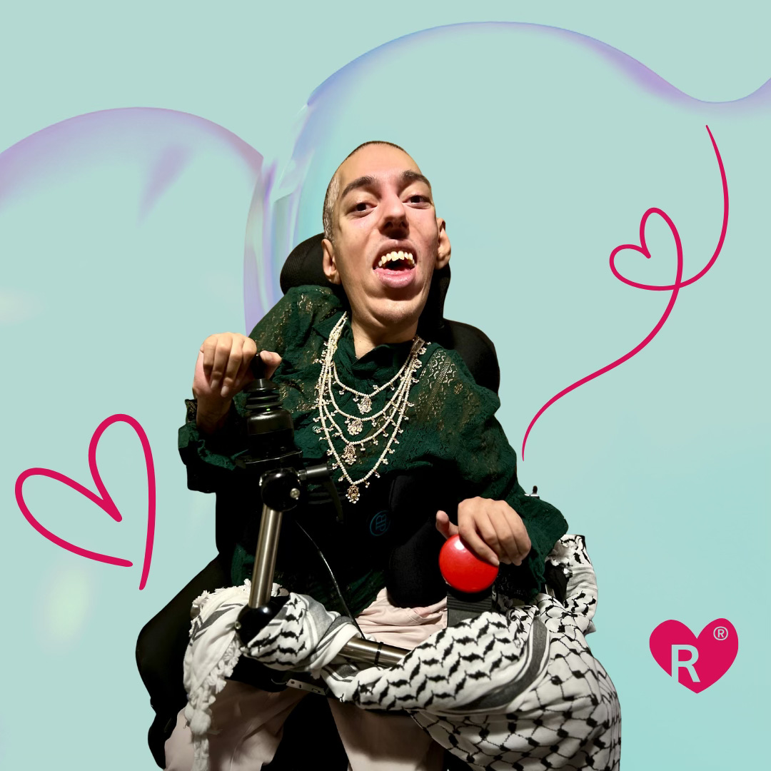 A close-up, cutout of Sulaiman (a wholeheartedly spicy Global Majority Disabled AF Oracle with a black buzzcut hair) sitting in his new(ish) power wheelchair and showcasing his radical outfit.