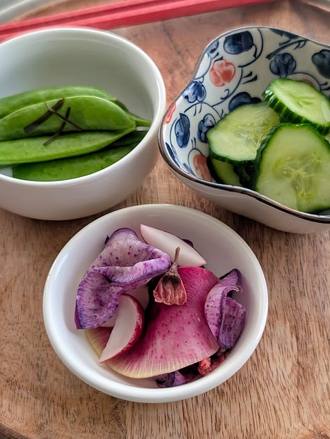 A colorful assortment of Japanese pickles, including crisp salt-brined cucumbers, deep brown soy-pickled shiitake mushrooms, and vibrant pickled fruit, arranged in small bowls.