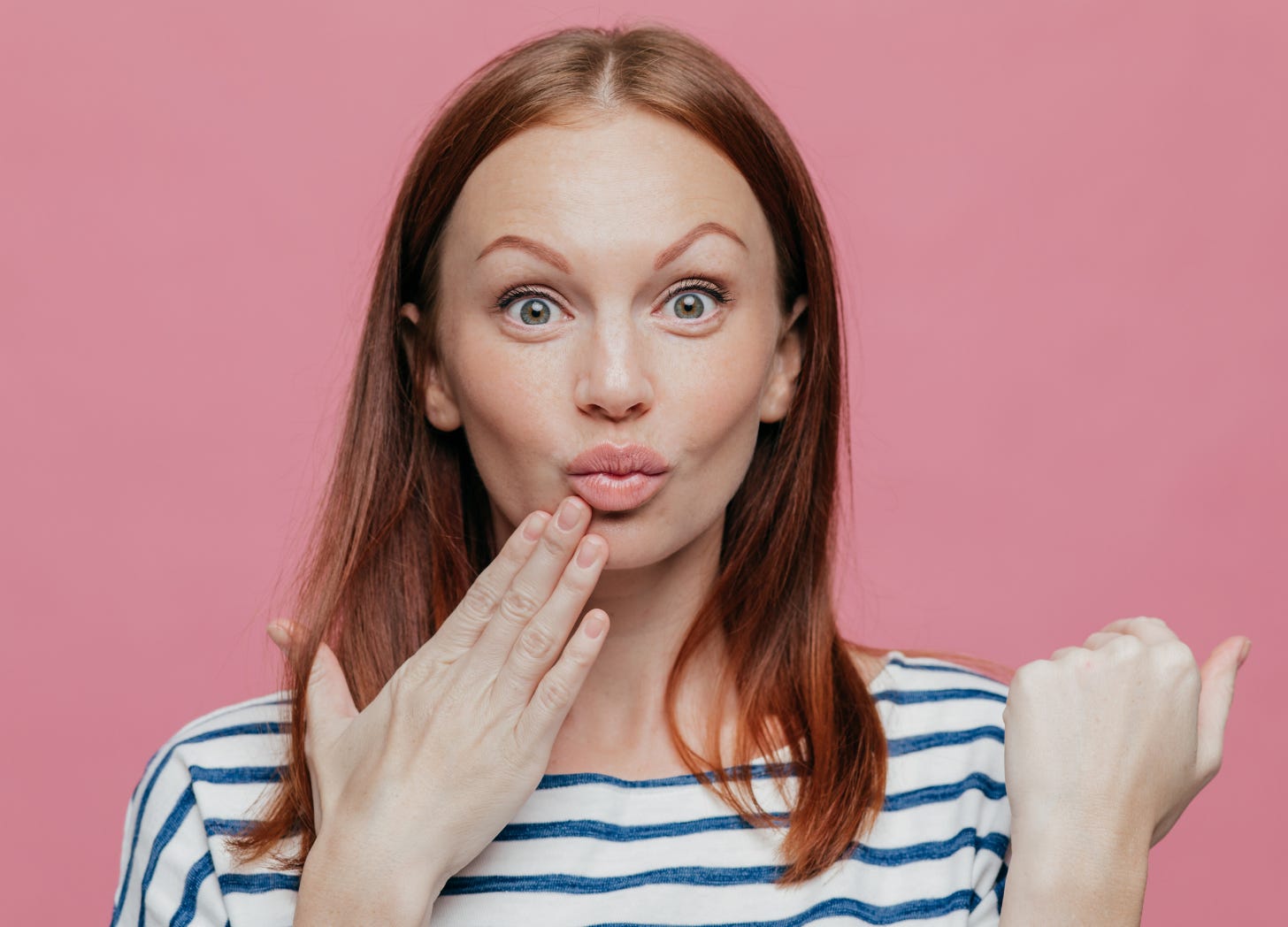 A middle-aged woman with raised eyebrows and a pursed mouth, holding her hand to her lips in a look of judgment or shock, as if reacting to something unconventional.