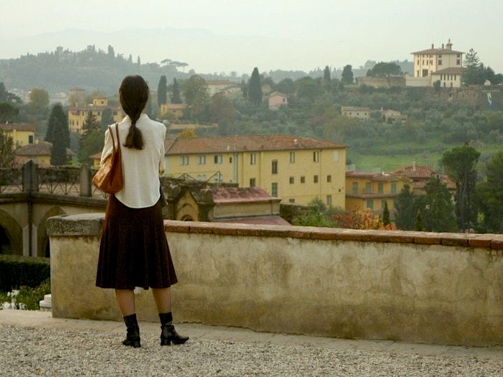 This may contain: a woman standing on top of a stone wall