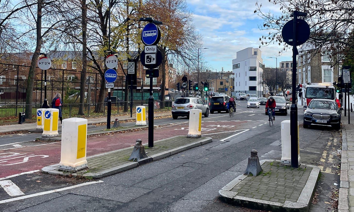View of a narrow road in London, with raised curb and metal bollards View of a narrow road in London, with raised curb and metal bollards