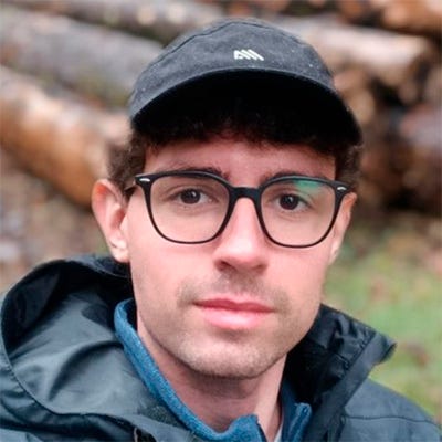 A imagem contém um homem, ele usa óculos e boné