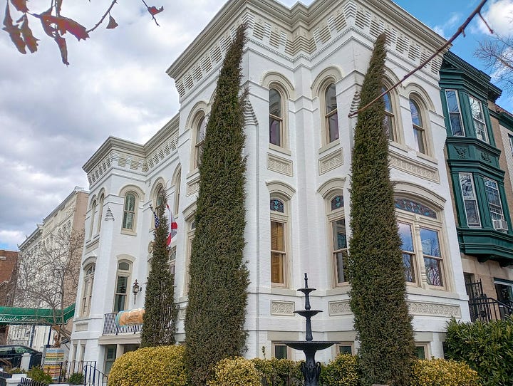 Grand Victorian building on left, and historical marker plus beachball mural on right