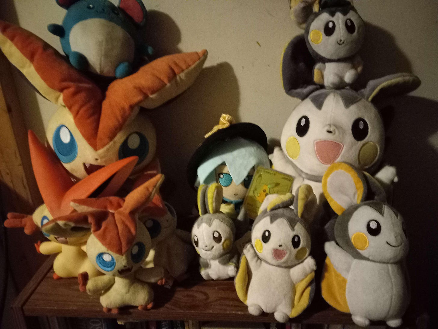 Oshi has a shelf full of Emolga and Victini plush toys (and a Marill) with a special 25th Anniversary Golden Pikachu card! Oshi has a shelf full of Emolga and Victini plush toys (and a Marill) with a special 25th Anniversary Golden Pikachu card!
