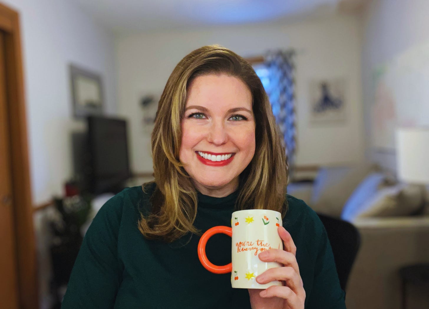A white woman over 40 smiles while holding a cute mug