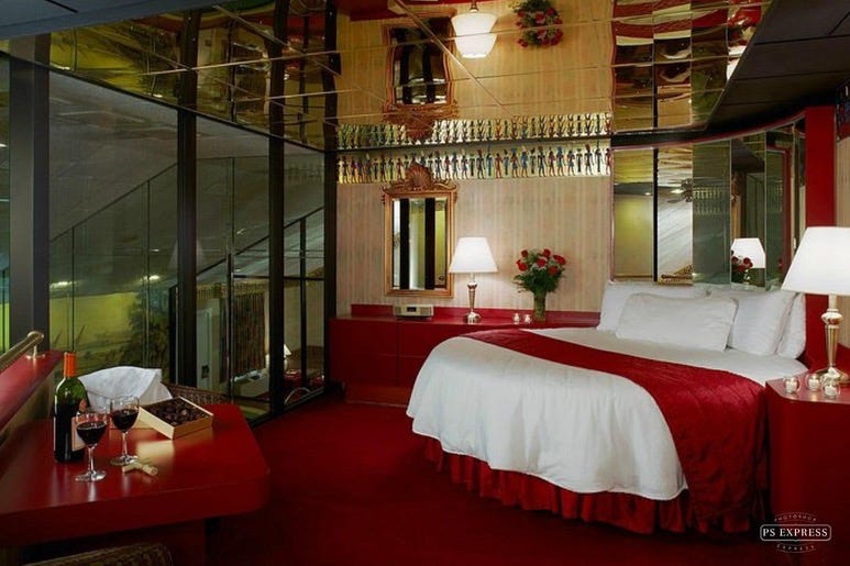 A bedroom with a red carpet and a bed

Description automatically generated