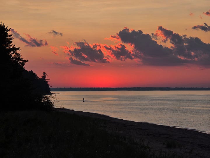 Shades of light pink in the sky mixed with clouds over Lake Superior.