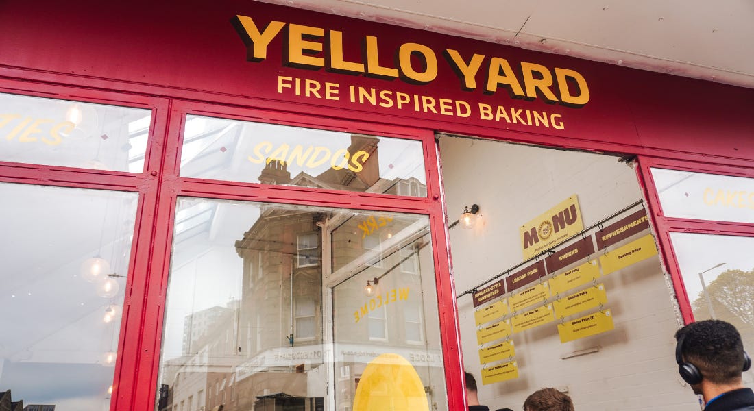 A burgundy shop front with a yellow sign that says 'Yello Yard' with a queue of people out the door