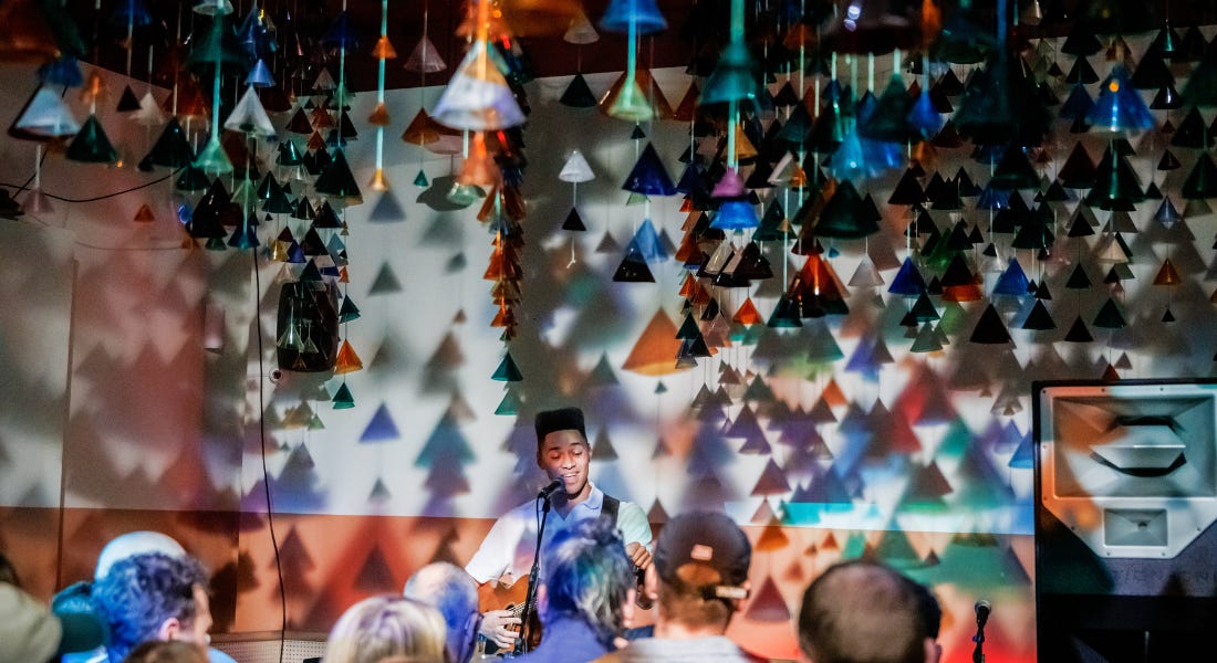 A concert venue with a man on stage with triangle decor hanging down A concert venue with a man on stage with triangle decor hanging down