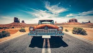 A Vintage Car is Driving Down a Road in ...