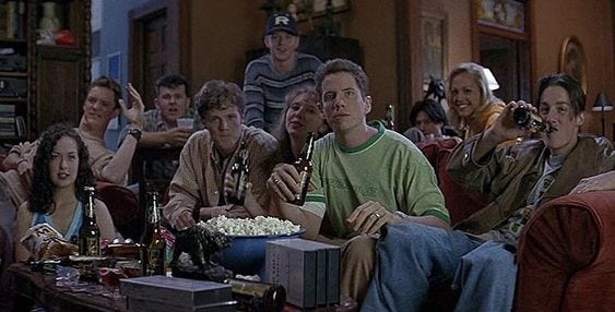 This may contain: a group of people sitting around each other in a living room watching something on tv