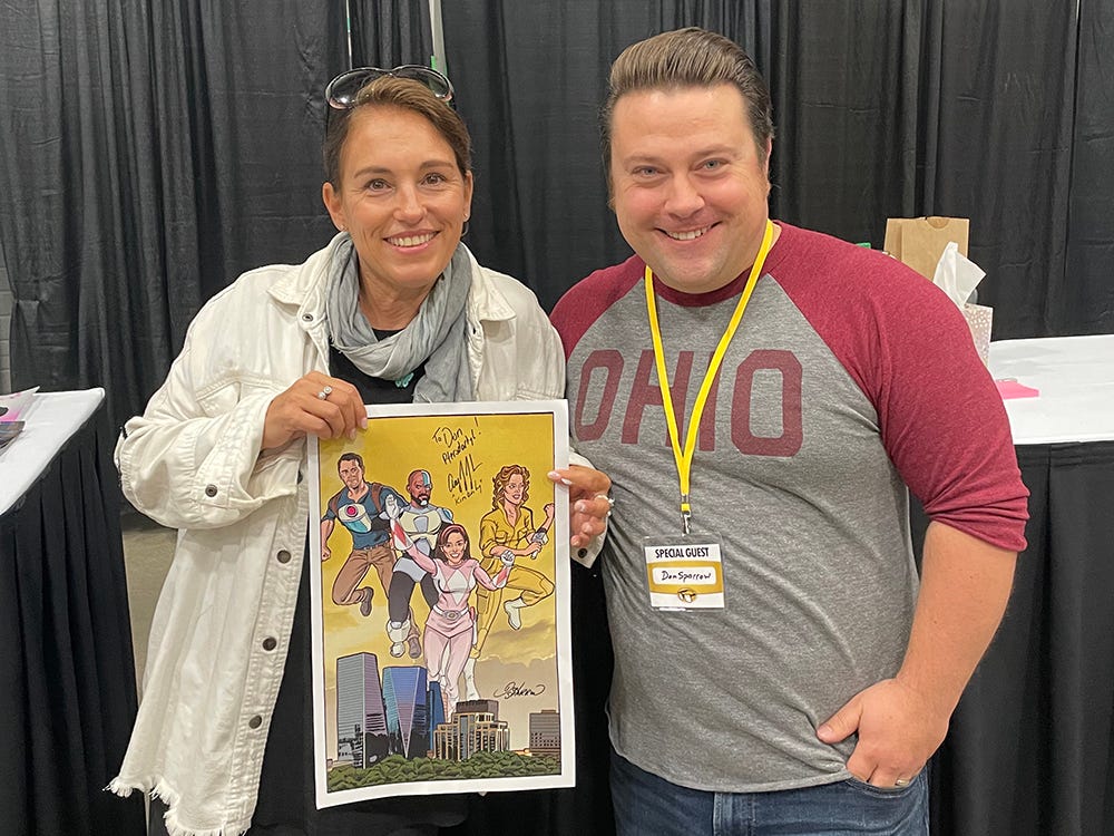 Actress and singer Amy Jo Johnson posing adoringly with renowned illustrator Don Sparrow.  Amy Jo Johnson delightedly holds a poster drawn by Don Sparrow, featuring a stunning rendition of Amy Jo in her Power Rangers costume.  