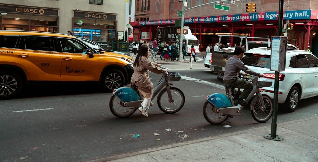 A couple of people riding bikes down a street A couple of people riding bikes down a street
