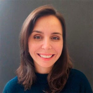 Foto de uma mulher branca, cabelos castanhos médios, sorrindo. Veste um suéter marinho Foto de uma mulher branca, cabelos castanhos médios, sorrindo. Veste um suéter marinho
