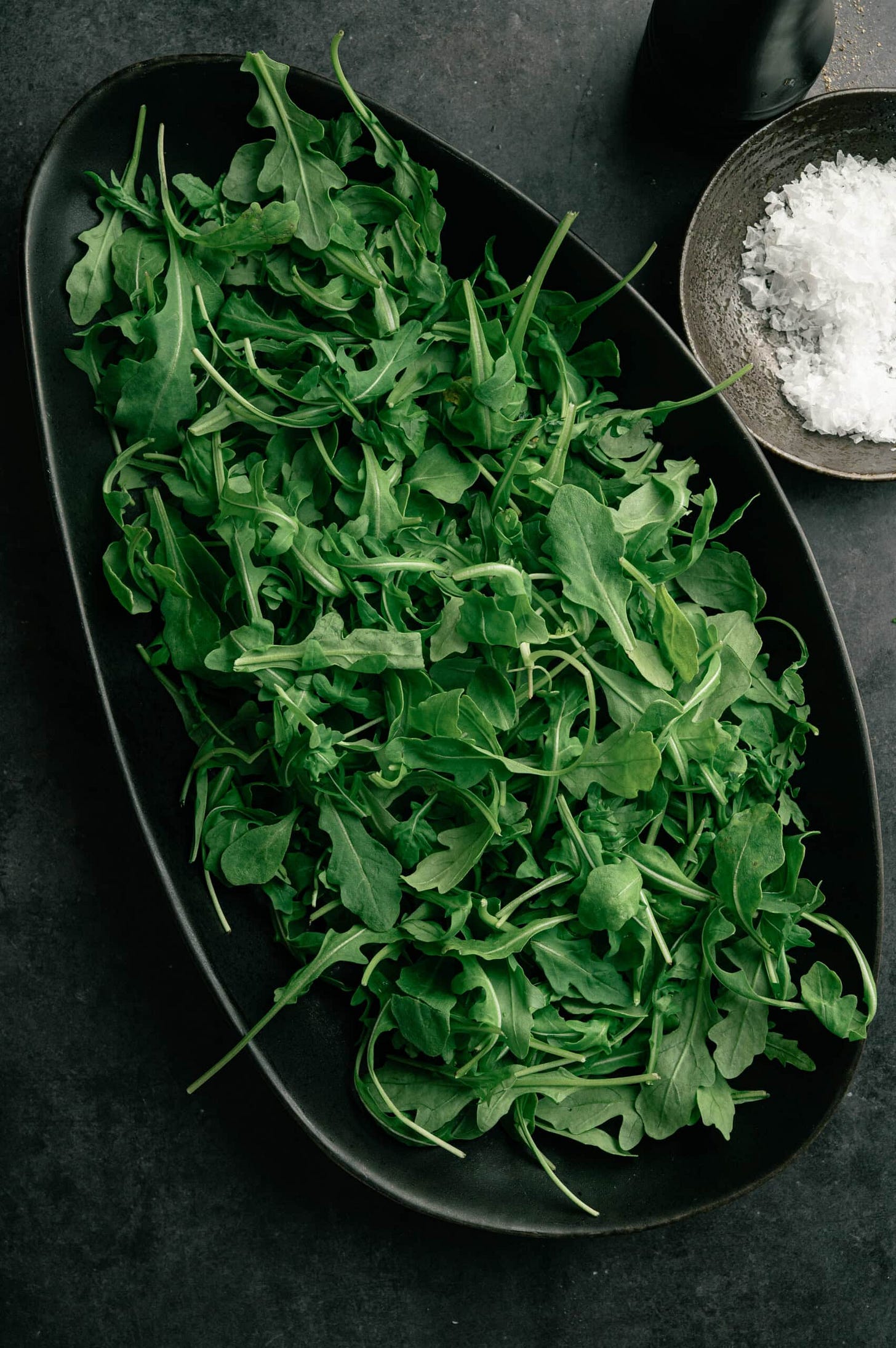 arugula salad in a black tray to serve avocado pear salad.