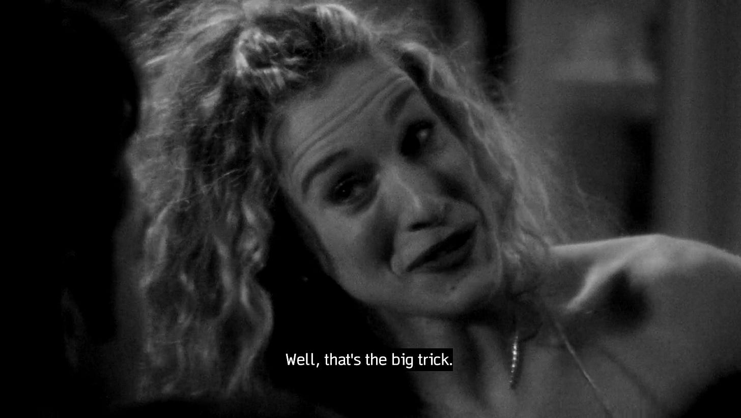 Screenshot em preto e branco de Carrie Bradshaw, na série Sex and the City, uma mulher loira de cabelos cacheados, deitada na cama, dizendo: "That's the big trick".