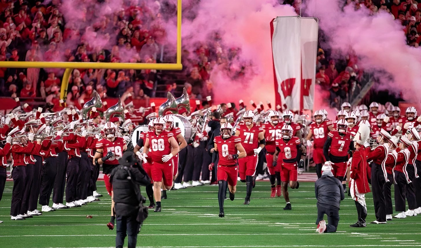Wisconsin Badgers football players run onto the field at Camp Randall Stadium for a night game. Wisconsin Badgers football players run onto the field at Camp Randall Stadium for a night game.