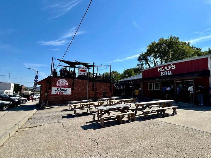 barbecue, picnic tables, signs, people in line