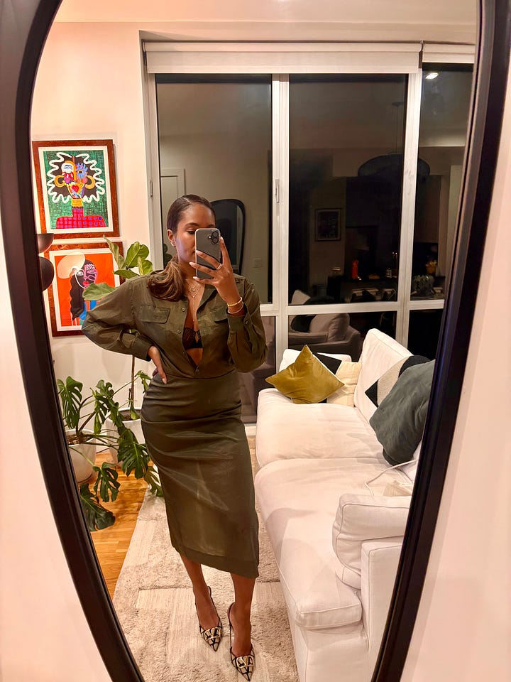 Two, full body mirror selfie photos side by side showing Black woman posed in a beautiful olive green monochrome outfit including an oversized, sherpa lined long leather coat and two-piece sheer collard button-up top and maxi skirt.