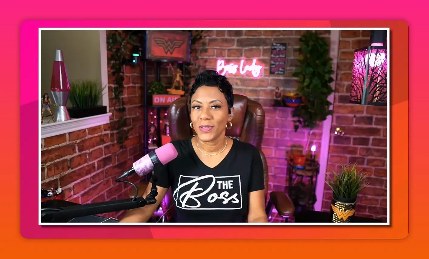 Host seated in live-stream studio with pink microphone, brick wall and neon sign visible Host seated in live-stream studio with pink microphone, brick wall and neon sign visible