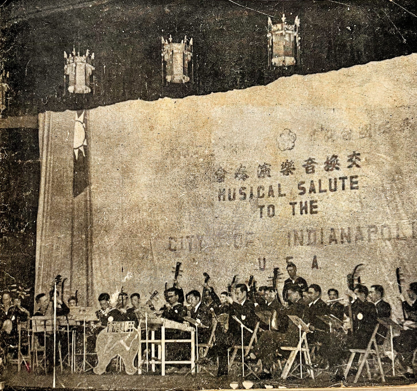 A grainy photo of a Taiwanese orchestra playing in front of a sign saying "Musical Salute to the City of Indianapolis" (1958)