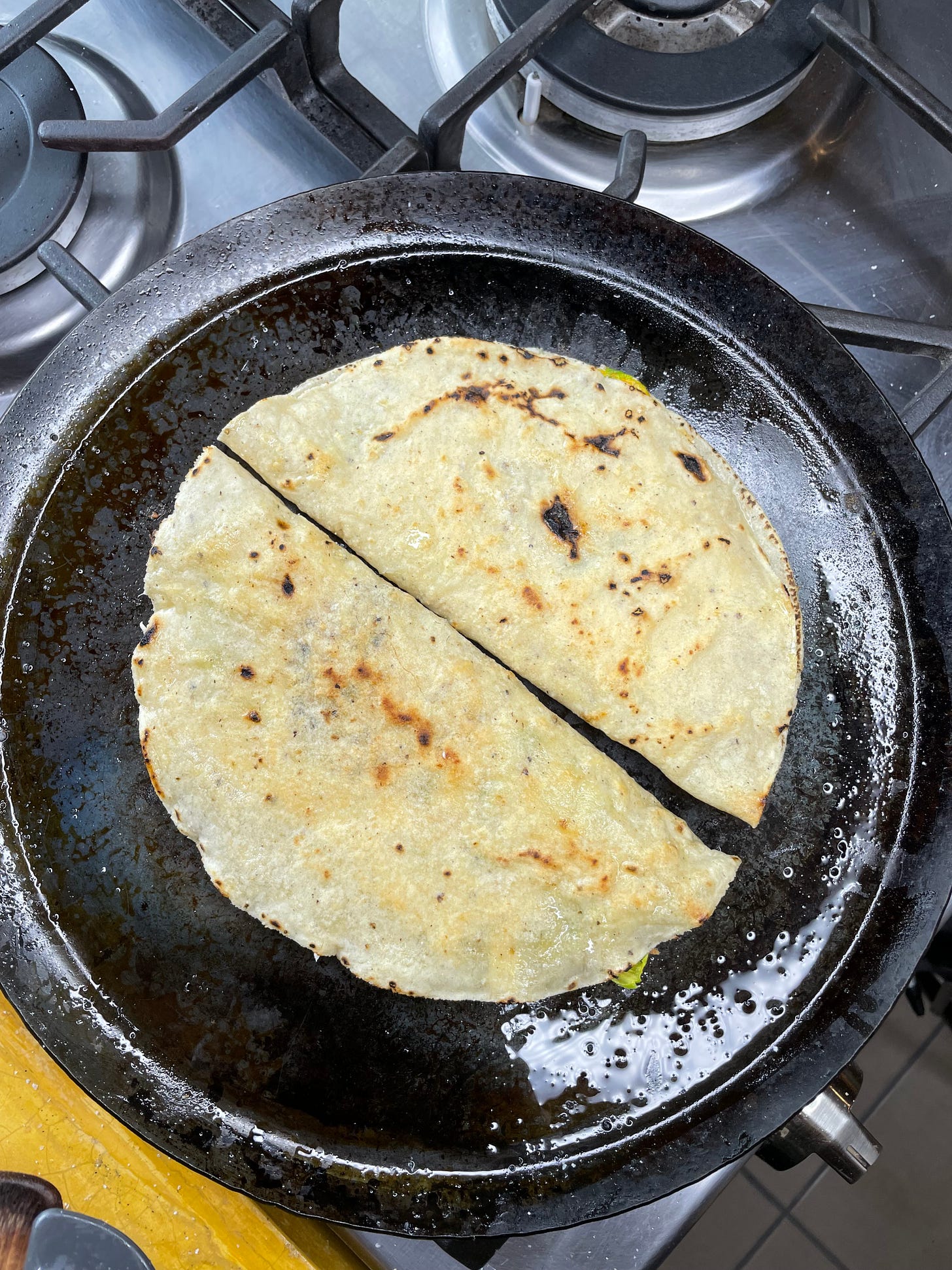 Two crispy squash blossom quesadillas on a comal.