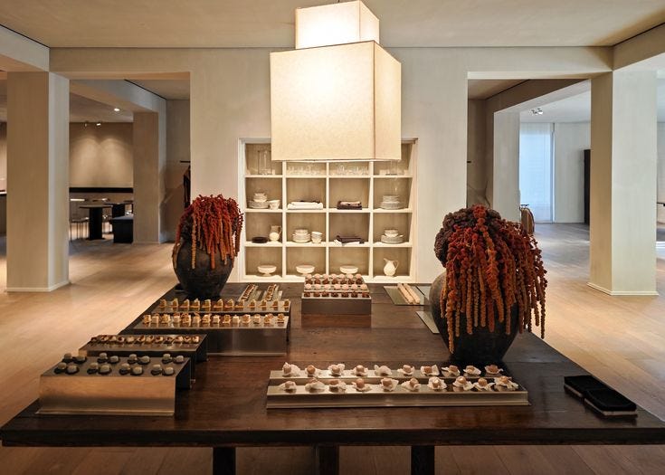 This may contain: a large room with many vases and plates on the table in front of it