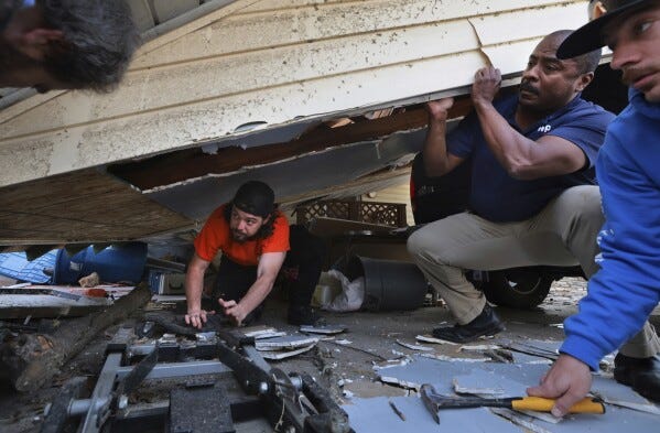 Matt Wolff, left, works underneath his carport with the help of his father-in-law Dempsey Watson and friend Tyler Umbright, right, as they work to stabilize after a severe storm in Bridgeton, Mo., Saturday, March 15, 2025. (Robert Cohen/St. Louis Post-Dispatch via AP)