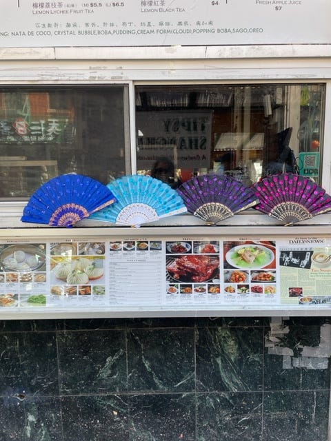 four Chinese fans atop a menu display outside a Chinatown restaurant