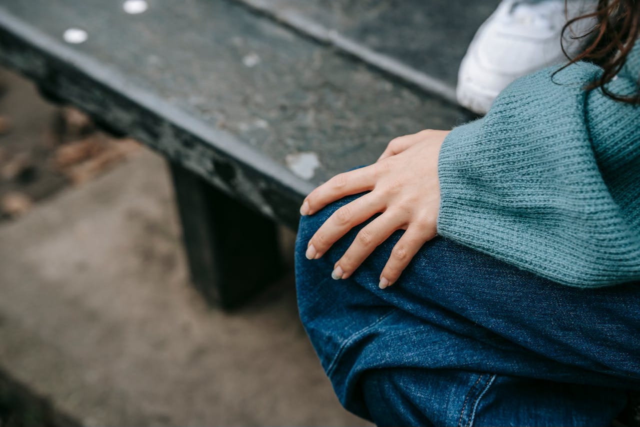 Cropped image of a woman with her hand on her knee atop her jeans. Cropped image of a woman with her hand on her knee atop her jeans.