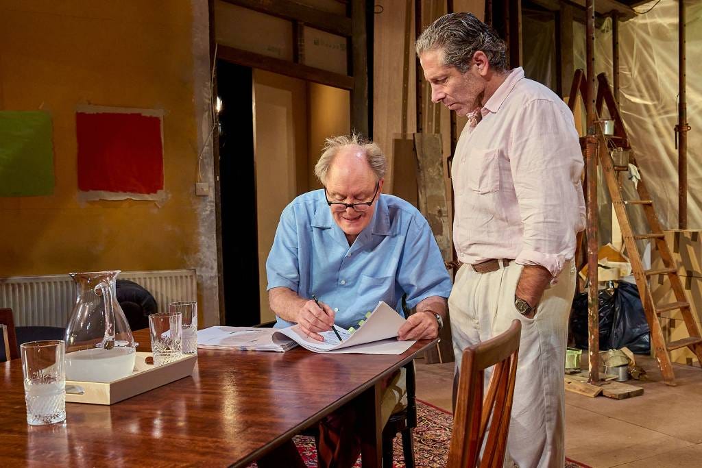 John Lithgow, as Roald Dahl, sitting  at the dining table and looking at proofs of his book while his publisher stands over him.