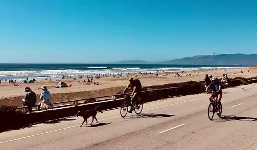 People riding bicycles on a road with a beach and people on the beach

AI-generated content may be incorrect.