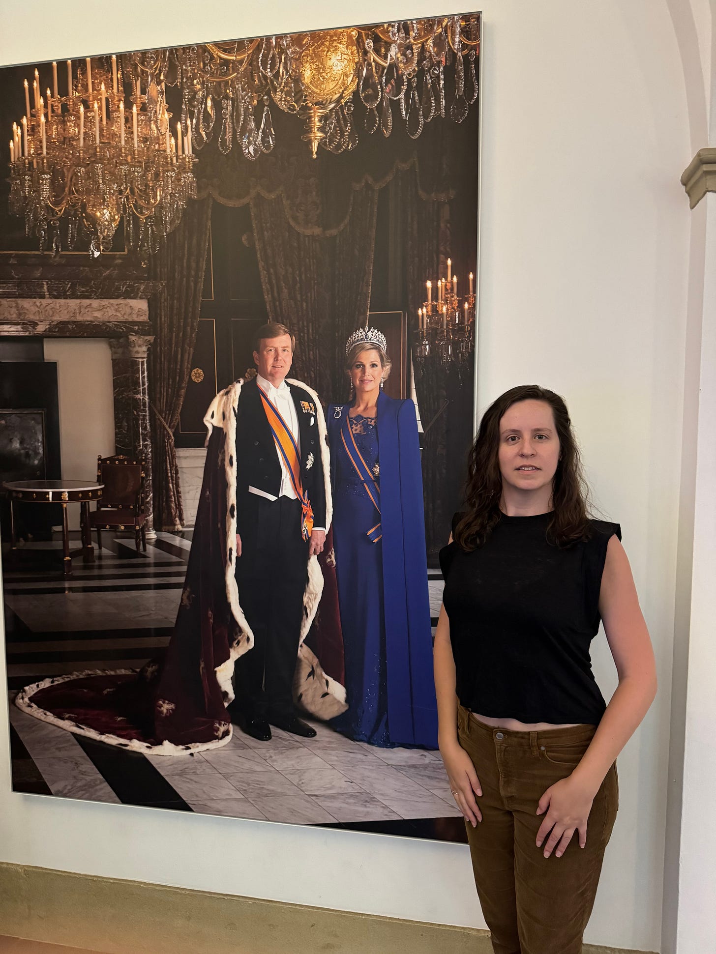 Dani stands next to a large wall decal of the royal monarchs of the Netherlands who's name she doesn't know