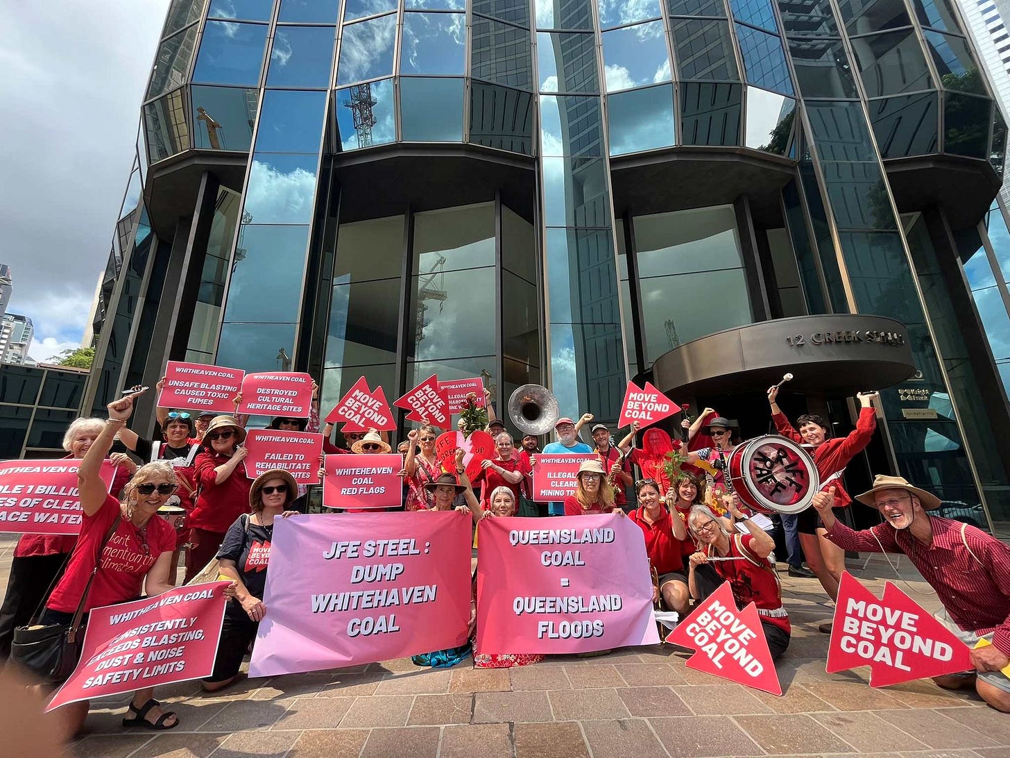 Photo of a 30 protestors wearing red outside the Brisbane office of JFE Steel and Whitehaven Coal