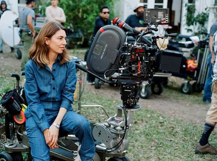 This may contain: a woman sitting on top of a motorcycle next to a camera