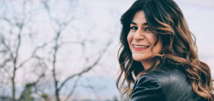 a woman outside, smiling oer her left shoulder