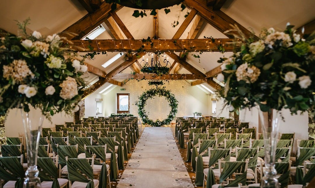 A room filled with lots of green chairs covered in white flowers A room filled with lots of green chairs covered in white flowers