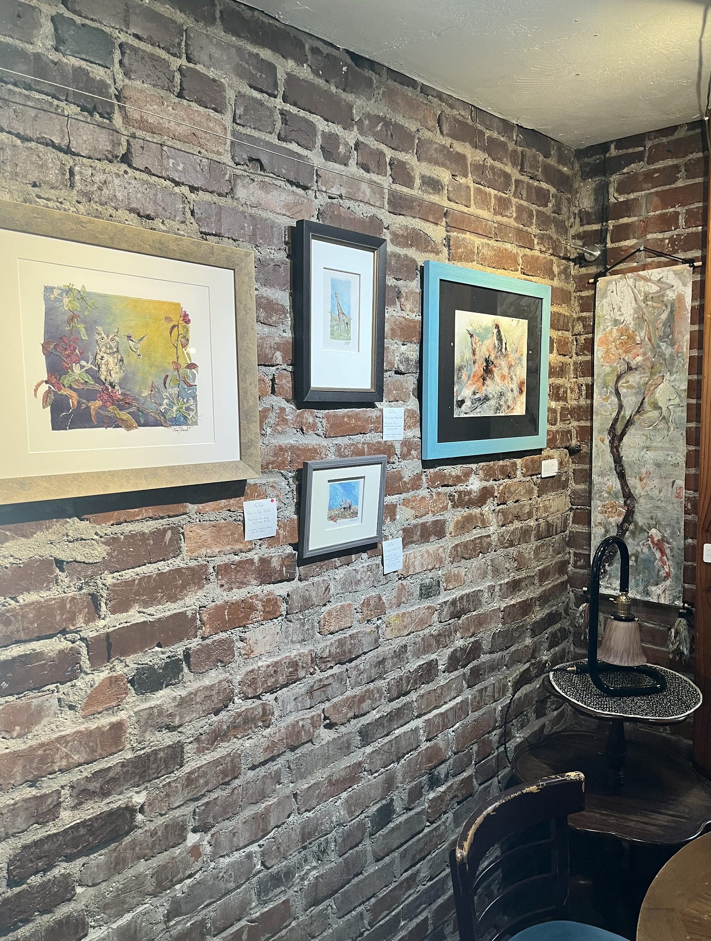paintings on a brick wall in a little nook for coffee