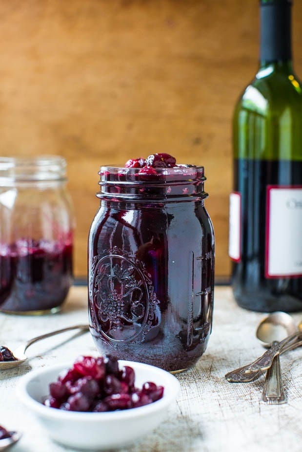 Cabernet Cranberry and Blueberry Sauce (vegan, GF) - Make your own cranberry sauce with amazing depth of flavor in 30 minutes! Easy recipe at averiecooks.com A mason jar of red wine cranberry sauce with a bottle of wine in the background.