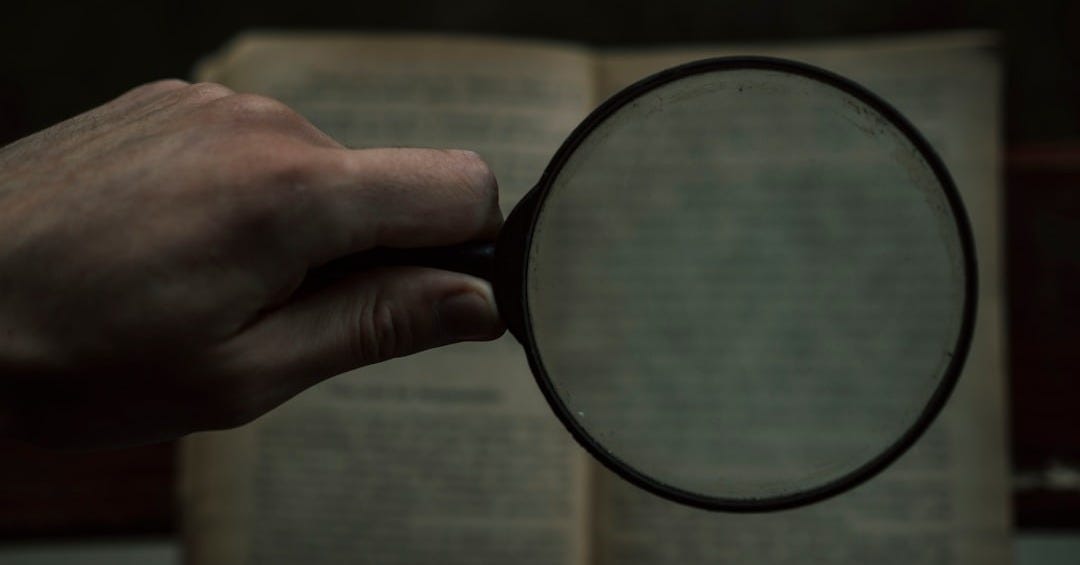person holding magnifying glass with black frame