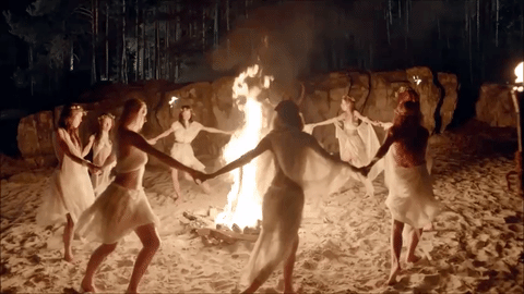 This may contain: a group of people dancing around a fire