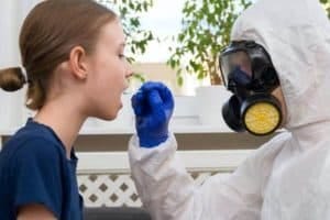 Male doctor in protective suit and mask taking swab sample from child. Coronavirus test.