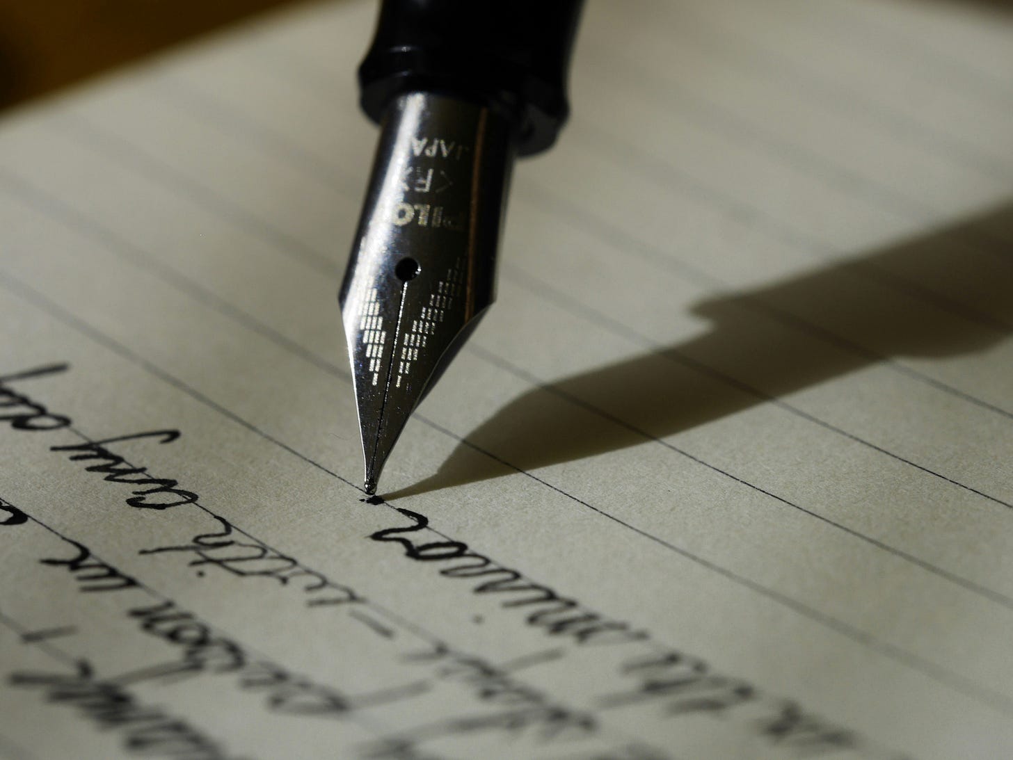 Close-up of a fountain pen nib writing black ink on lined paper Close-up of a fountain pen nib writing black ink on lined paper