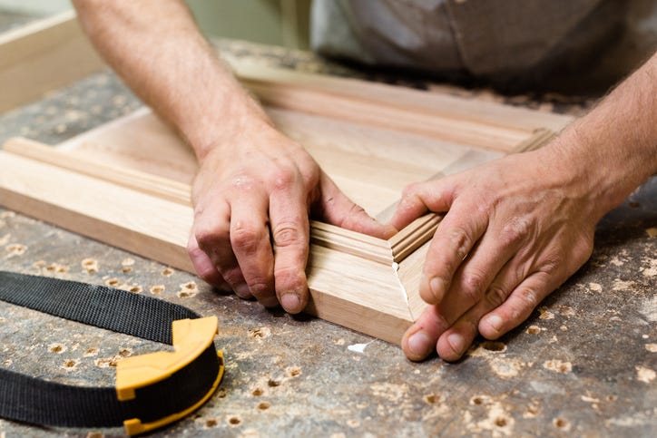 White man's hands assembling a light wood shaker cabinet door