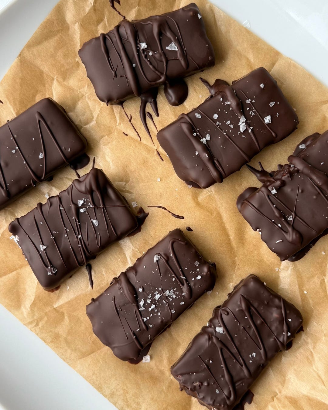 Healthy coconut and chocolate snack bars stacked on a plate with a bite taken out, showing the creamy coconut center.