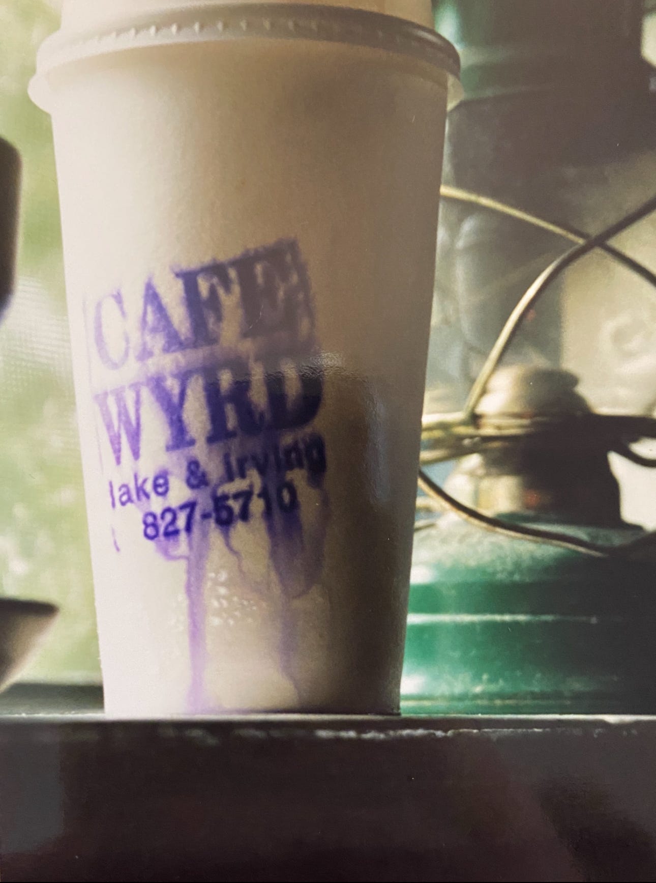 An old paper to-go coffee cup from Cafe WYRD, which was on the corner where one might see someone waiting for the either the 17 or the 21 bus