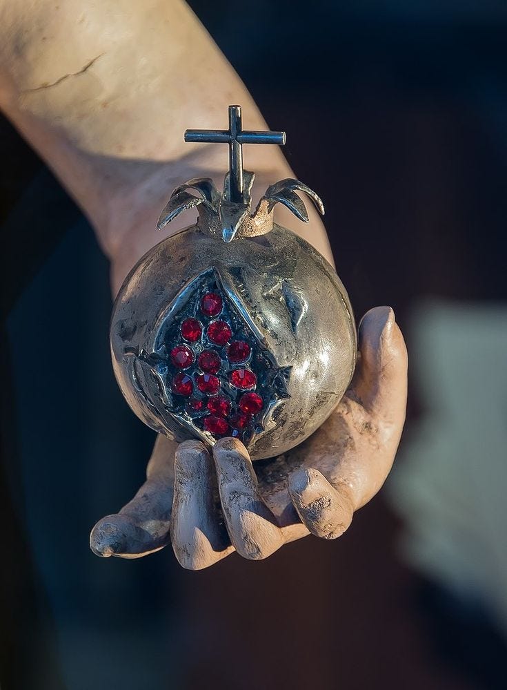 This may contain: a person's hand holding a glass ball with a cross on it and red berries in the middle