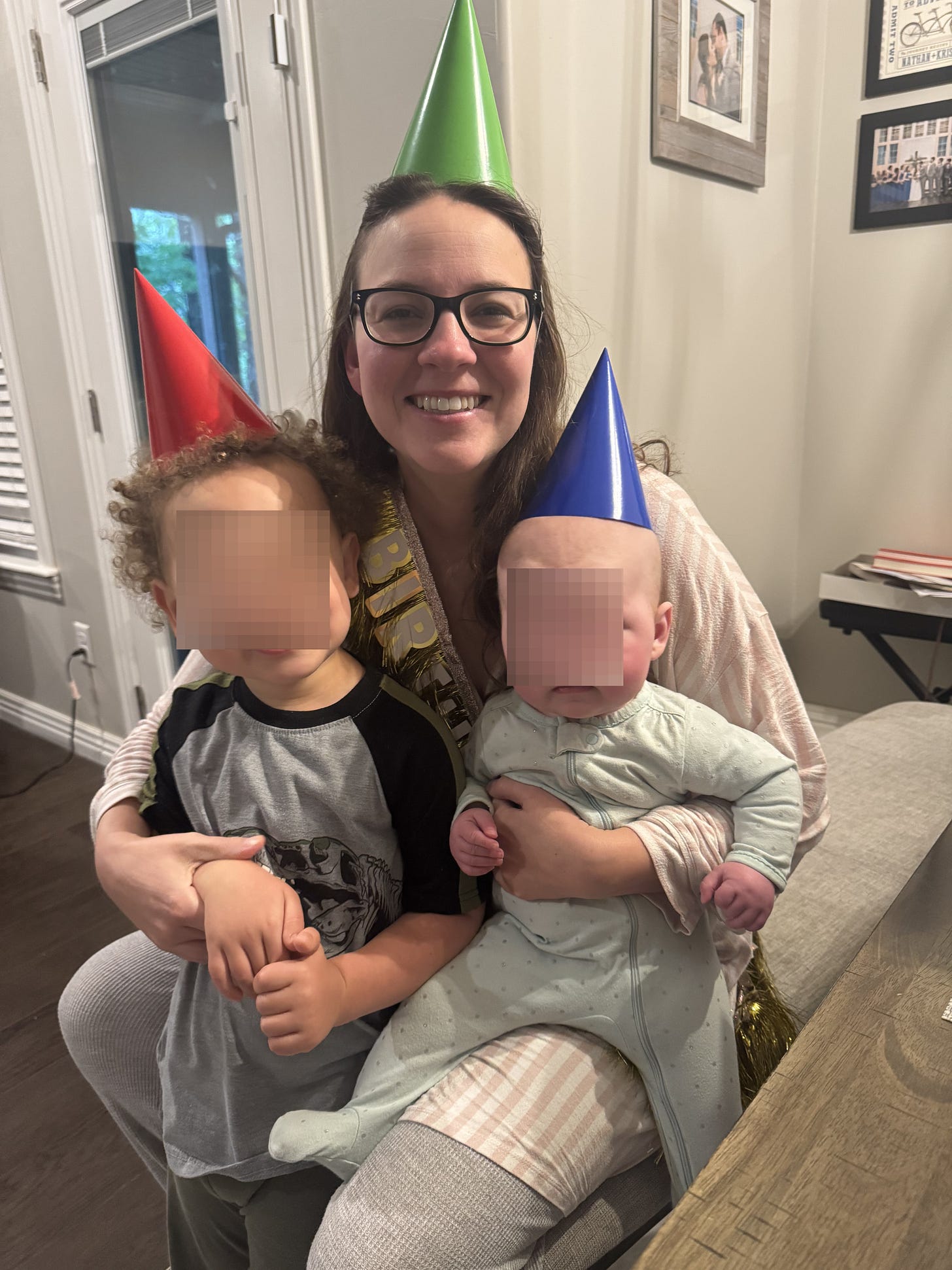 A mom in a birthday hat holds her two children A mom in a birthday hat holds her two children